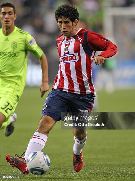 Edgar Mejia of Chivas de Guadalajara dribbles against Miguel Montano of the Seattle Sounders FC on October 12, 2010 at Qwest Field in Seattle,...
