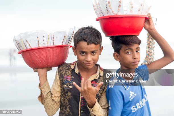 Cox´s Bazar, Bangladesh Two boys from Bangladesh, street vendors who have to do child labor are posing into the camera and are showing his fingers as...