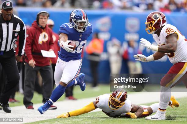 Saquon Barkley of the New York Giants extends in an attempt to reach the first down against Josh Norman and Da'Ron Payne of the Washington Redskins...