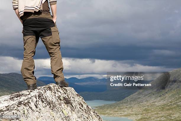 hiker on cliff edge - pantalón fotografías e imágenes de stock