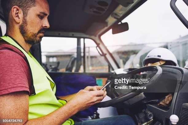 construcción industria trabajo mensajes de texto en el teléfono dentro de un camión. - conductor oficio fotografías e imágenes de stock