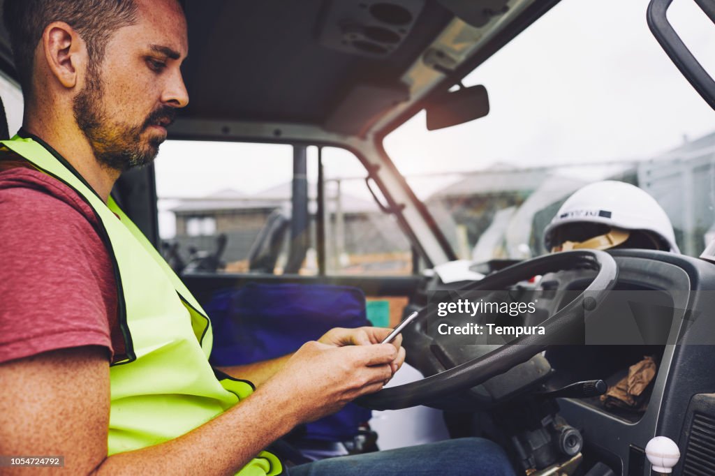 Construction industrie ouvrier SMS sur le téléphone à l’intérieur d’un camion.