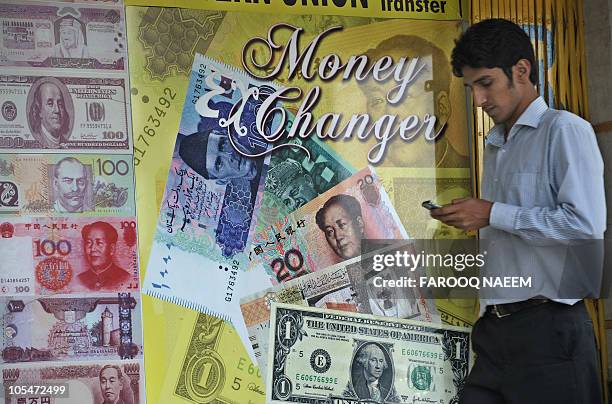 Pakistani man walks past an currency exchange shop in Islamabad on October 14, 2010. The US dollar fell against most Asian currencies while the...