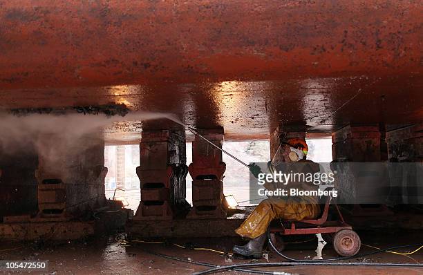 An employee cleans the hull of an ammunitions barge as it sits in a dry dock at the A&P Falmouth shipyard operated by A&P Group Ltd. In Falmouth,...