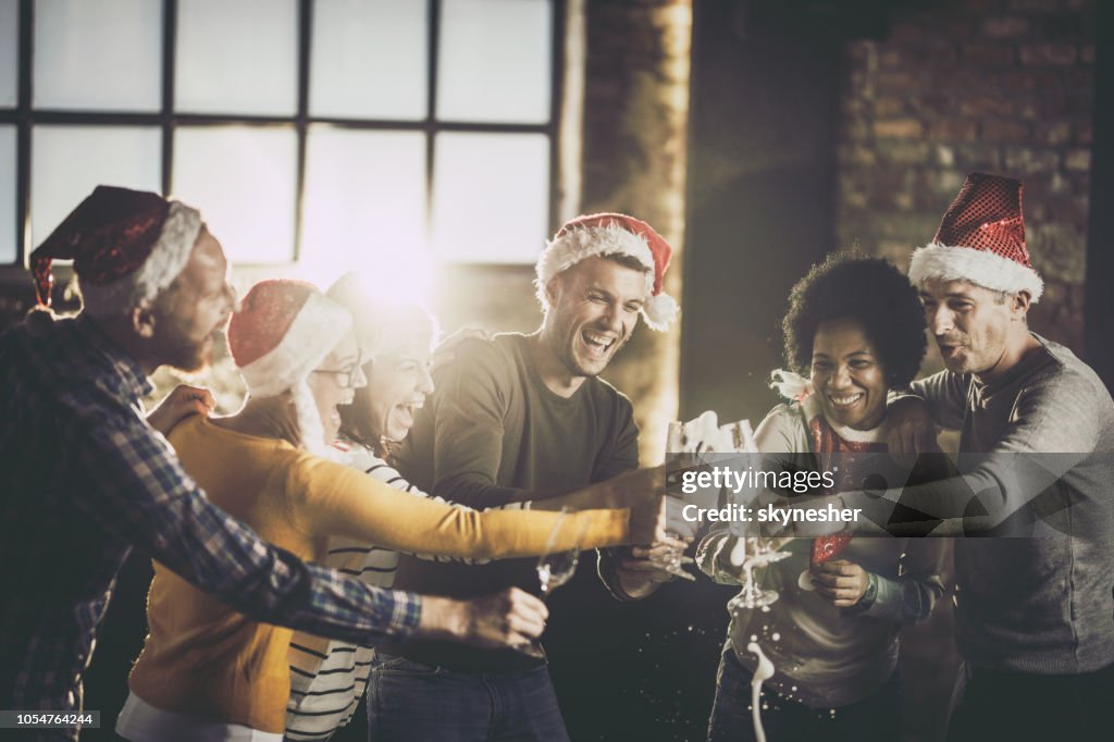 Équipe de joyeux affaires s’amuser lors de l’ouverture de champagne au cours de la célébration de Noël au bureau.