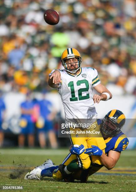 Quarterback Aaron Rodgers of the Green Bay Packers throws the ball as he is tackled by linebacker Matt Longacre of the Los Angeles Rams at Los...
