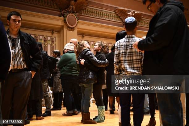 People hug after a vigil to remember the victims of the shooting at the Tree of Life synagogue the day before, at the Allegheny County Soldiers...