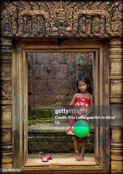 Cambodian little girl with a green balloon in Banteay Srei temple gate, Siem Reap Province, Angkor, Cambodia on July 26, 2006 in Angkor, Cambodia.