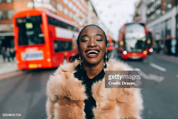 portrait of modern black woman in oxford street in london, uk - fake fur stock pictures, royalty-free photos & images