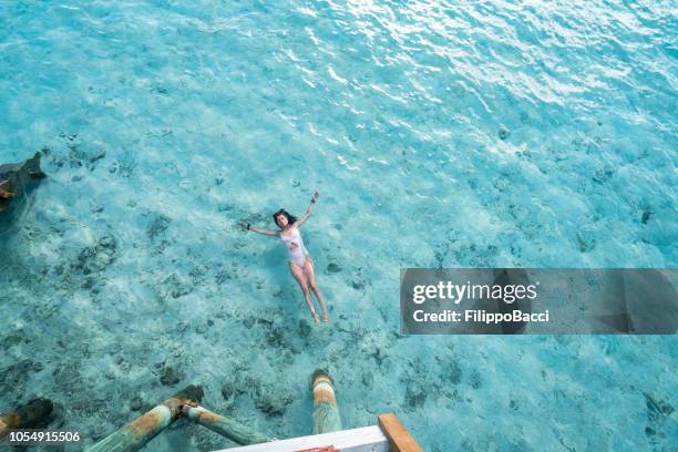 jeune femme adulte relaxante à la mer - couché de soleil photos et images de collection