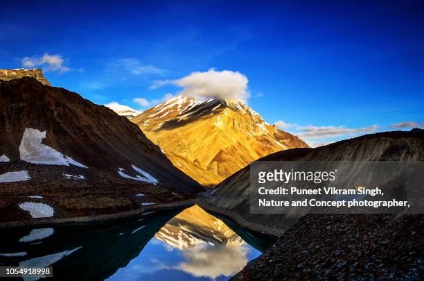 a mountain with cloud over the peak in front of suraj tal lake in lahaul valley, himachal pradesh - himalayas sunrise stock pictures, royalty-free photos & images