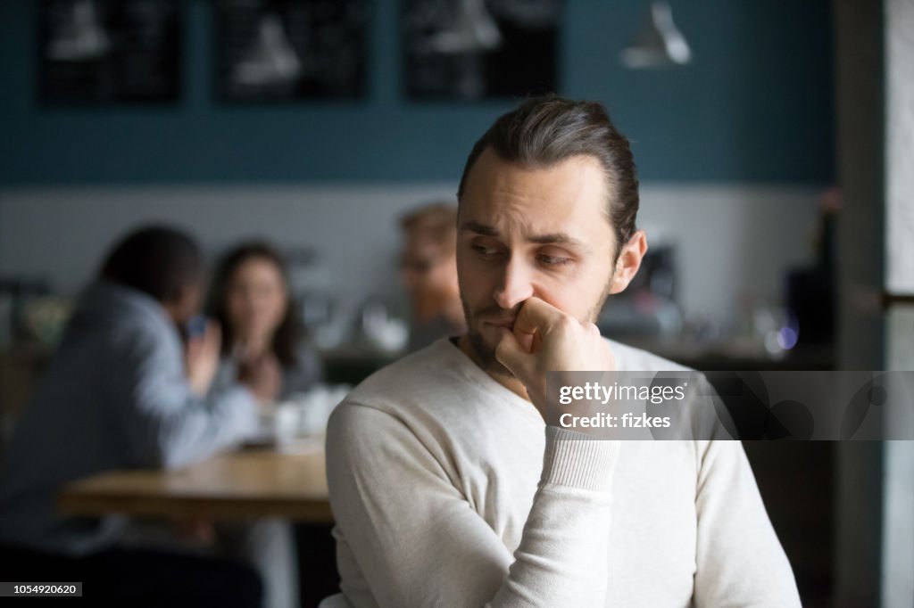 Upset male outcast feel lonely sitting alone in cafe