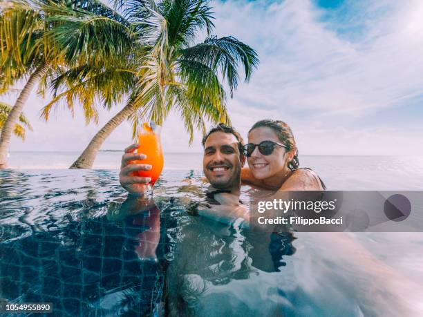 young adult couple doing a selfie in the swimming pool in a paradisiac island - beach palm trees drink stock pictures, royalty-free photos & images