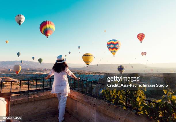 schöne asiatische frau beobachten bunten heißluftballons fliegen über das tal in kappadokien, turkey.turkey kappadokien märchenhafte landschaft der berge. türkei kappadokien märchenhafte landschaft der berge. - heißluftballon stock-fotos und bilder