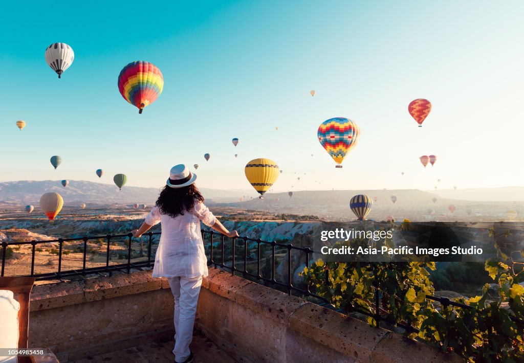 美しいアジアの女性は、カラフルな熱気球カッパドキア, カッパドキア Turkey.Turkey おとぎ話風景山の谷の上空を見ています。トルコ カッパドキア山の童話風景。