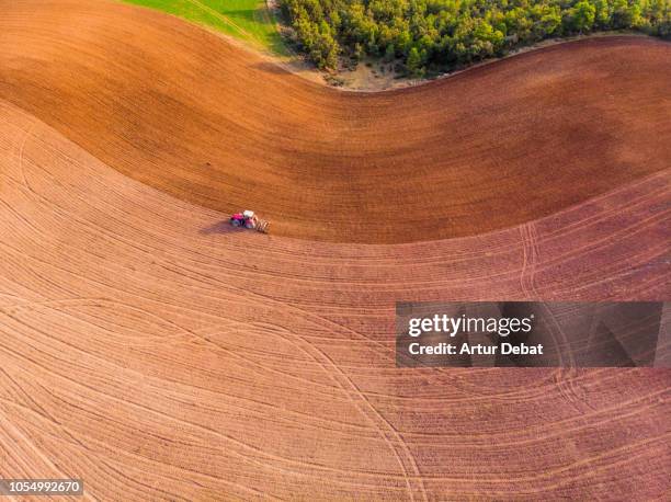 aerial view with drone of tractor plowing the land in the countryside. - arado maquinaria de agricultura - fotografias e filmes do acervo