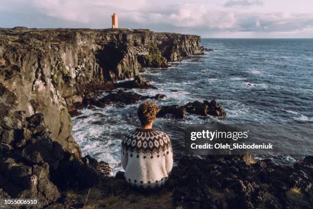 mann, blick auf den malerischen blick auf leuchtturm in island - halbinsel reykjanes stock-fotos und bilder