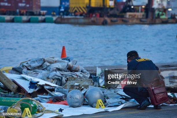 Forensic investigator looks through the remains of Lion Air flight JT 610 at the Tanjung Priok port on October 29, 2018 in Jakarta, Indonesia. Lion...
