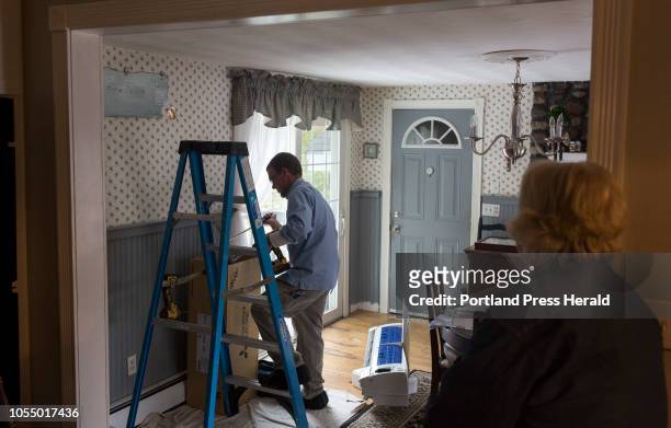 Dale Bois watches from the kitchen as Aaron Sinclair, of Dave's World, installs a heat pump in her home on September 25, 2018. Bois said she and her...