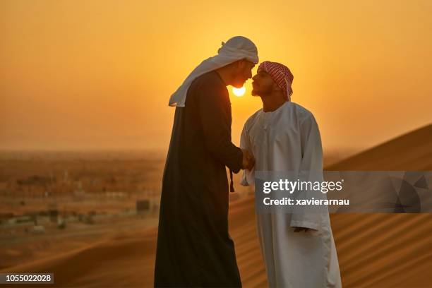 orientalische männer gruß in einer traditionellen arabischen kultur in wüste bei sonnenaufgang - dubai desert stock-fotos und bilder