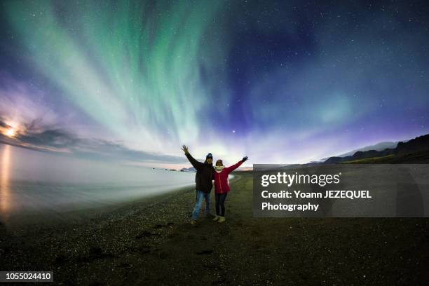 couple admiring aurora borealis in iceland - iceland aurora stock pictures, royalty-free photos & images