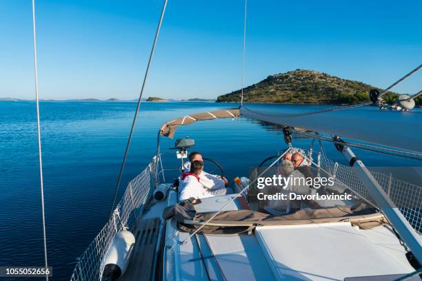 five men, two seniors, enjoying sailing while talking on boat - croatia sailing stock pictures, royalty-free photos & images