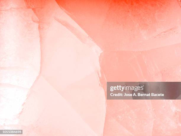 full frame of the textures formed of a block of cracked ice, on a pale pink and red background. - ice pattern stock pictures, royalty-free photos & images