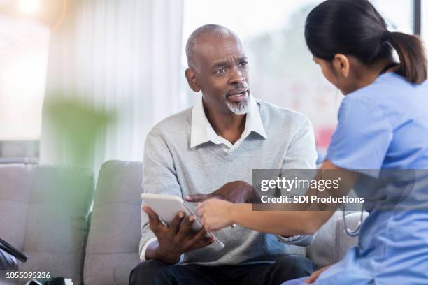 upset senior man talks with doctor - digital health display stock pictures, royalty-free photos & images