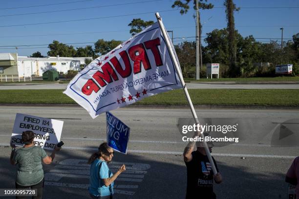 Man waves a flag in support of U.S. President Donald Trump as demonstrators protest in Englewood, Florida, U.S., on Wednesday, Oct. 17, 2018. Mother...