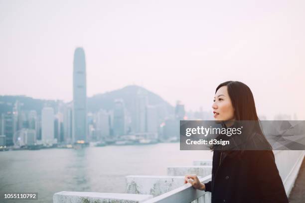 beautiful asian woman overlooking cityscape from roof top terrace - asian woman smiling sunrise stock pictures, royalty-free photos & images