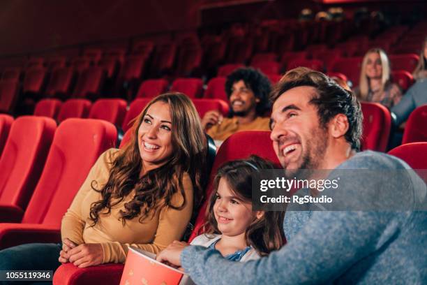 smiling family in the cinema - young couple at movie together imagens e fotografias de stock