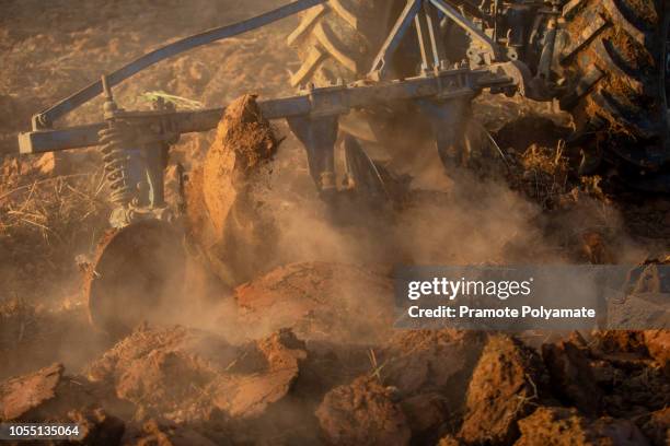 asian agricultural workers use tractors to prepare soil for planting. - aratro foto e immagini stock