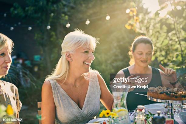 mature woman eating at dinner party in garden - outdoor dining 個照片及圖片檔