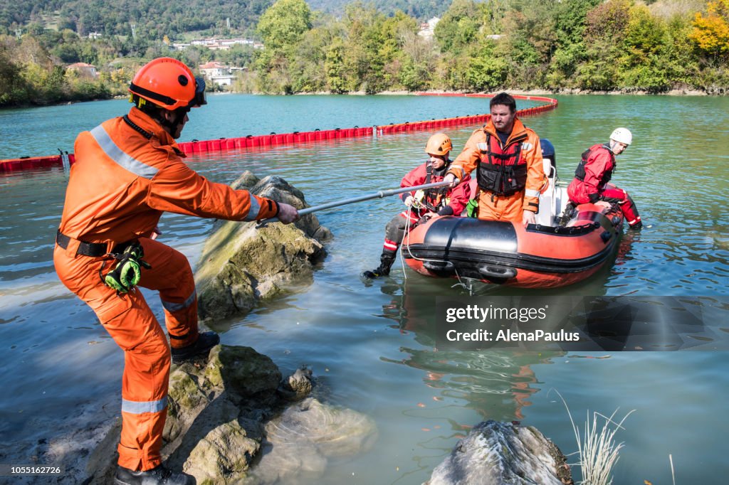 Dam construction on the river - rescue operation with a boat, oil spill