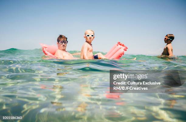 father and sons with inflatable mattress in sea, portrait, calvi, corsica, france - corsica family stock pictures, royalty-free photos & images