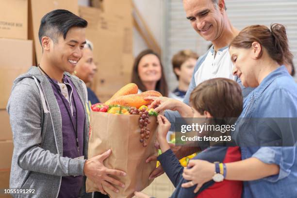 multi-ethnic group of volunteers work at food bank. - hungry people stock pictures, royalty-free photos & images