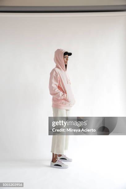 a beautiful, young muslim woman wearing a black hijab, black baseball cap, white jeans and a pink hoodie photographed in studio setting. - white pants stock-fotos und bilder