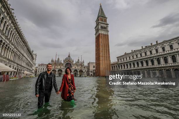 Couple of tourists walk in "Piazza San Marco" on October 29, 2018 in Venice, Italy. Due to the exceptional level of the "acqua alta" or "High Tide"...