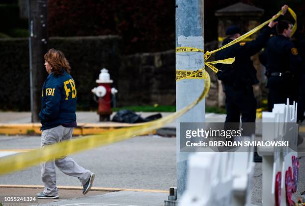 Members of the FBI walk past a memorial outside the Tree of Life synagogue after a shooting there left 11 people dead in the Squirrel Hill...