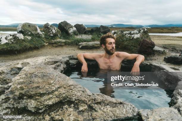 Homem a nadar na piscina quente na Islândia