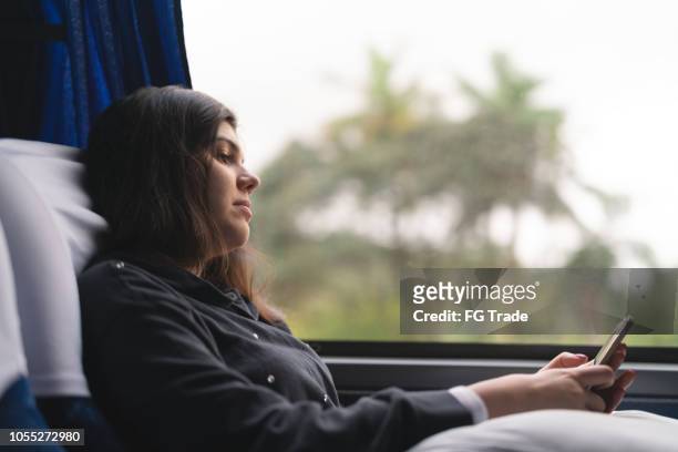 femme à l’aide de mobile au bus - car journey photos et images de collection