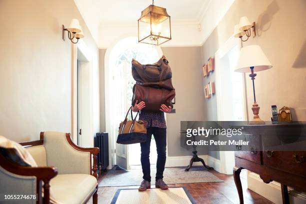 young man carrying stack of luggage in hotel lobby - schleppe kleidung stock-fotos und bilder