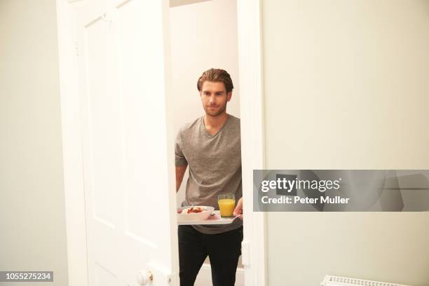 young man carrying breakfast tray into bedroom - man tray food holding stock pictures, royalty-free photos & images