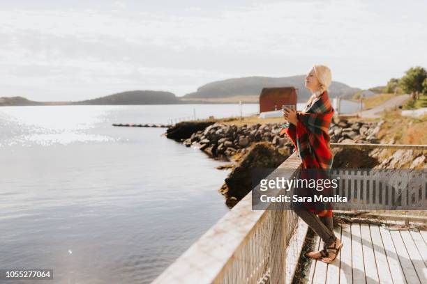 woman enjoying morning drink on balcony by sea, halifax, canada - halifax regional municipality nova scotia stockfoto's en -beelden