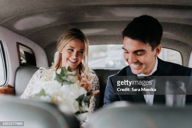 bride and bridegroom in backseat of car - hochzeitspaar stock-fotos und bilder