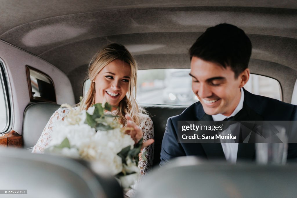 Bride and bridegroom in backseat of car