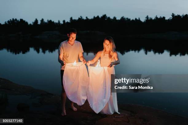 couple releasing sky lanterns by lake, algonquin park, canada - releasing lanterns stock pictures, royalty-free photos & images