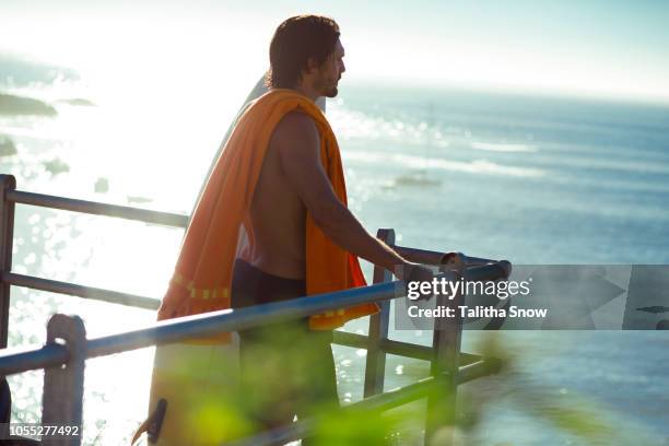 mid adult male surfer looking out at sea from balcony, cape town, camps bay beach, cape town, south africa - beach balcony stock pictures, royalty-free photos & images