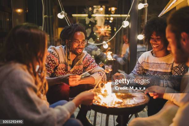 friends roasting marshmallows at back yard - winter friends stock pictures, royalty-free photos & images