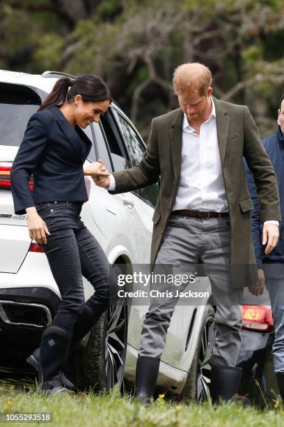 Prince Harry, Duke of Sussex helping Meghan, Duchess of Sussex step over mud on their visit to the North Shore to dedicate a 20-hectare area of...